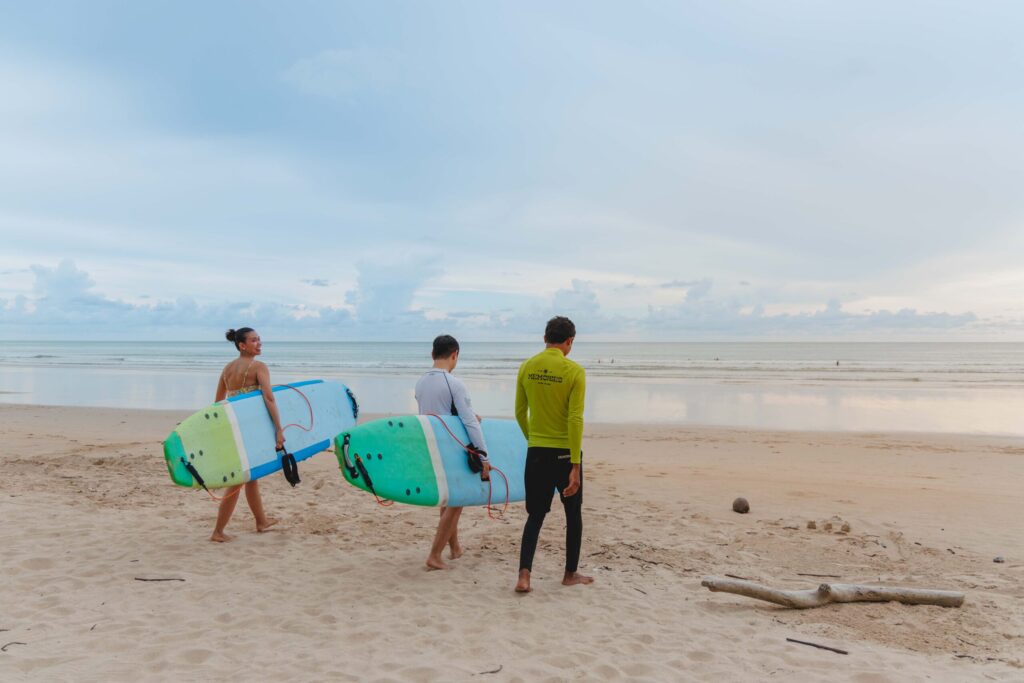 Participants carry surfboards to the beach for Thailand Surf Therapy experience in Phang-nga.