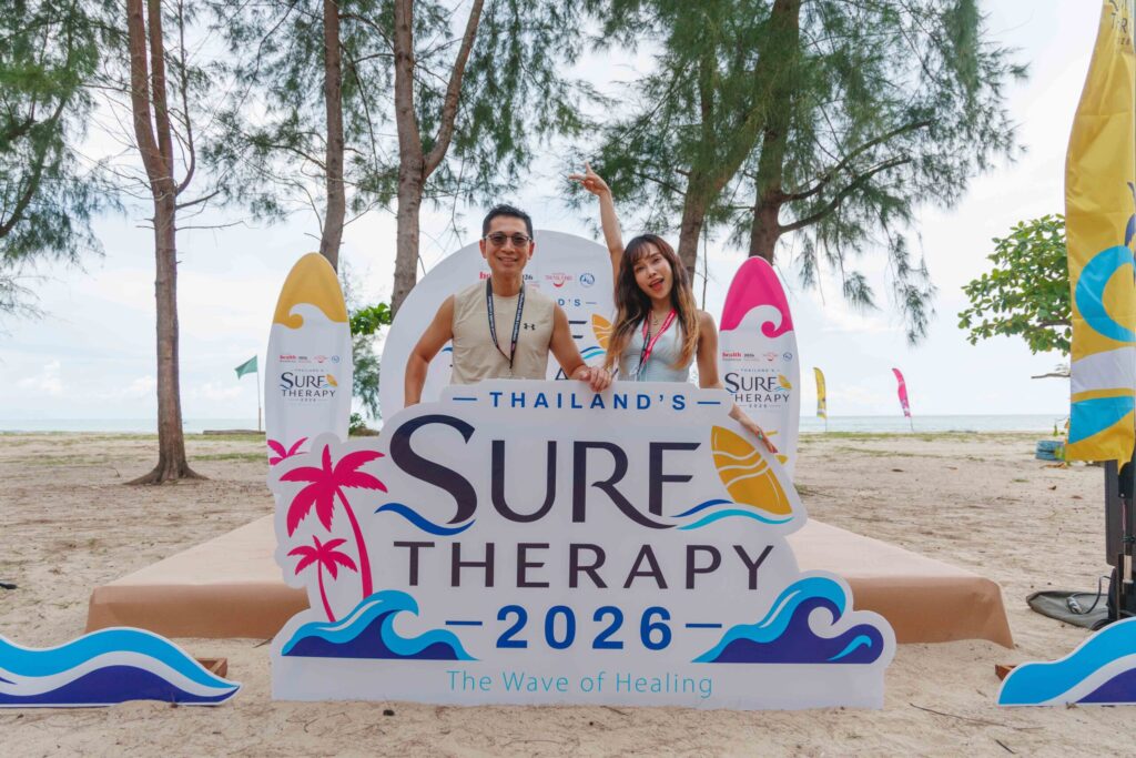 Participants pose with Thailand Surf Therapy 2026 signage at a coastal wellness event in Phang-nga.