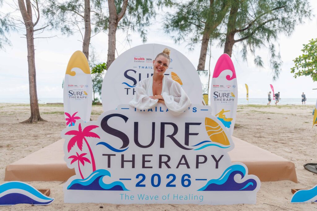 Guest poses at Thailand Surf Therapy 2026 beach event promoting coastal wellness in Phang-nga.