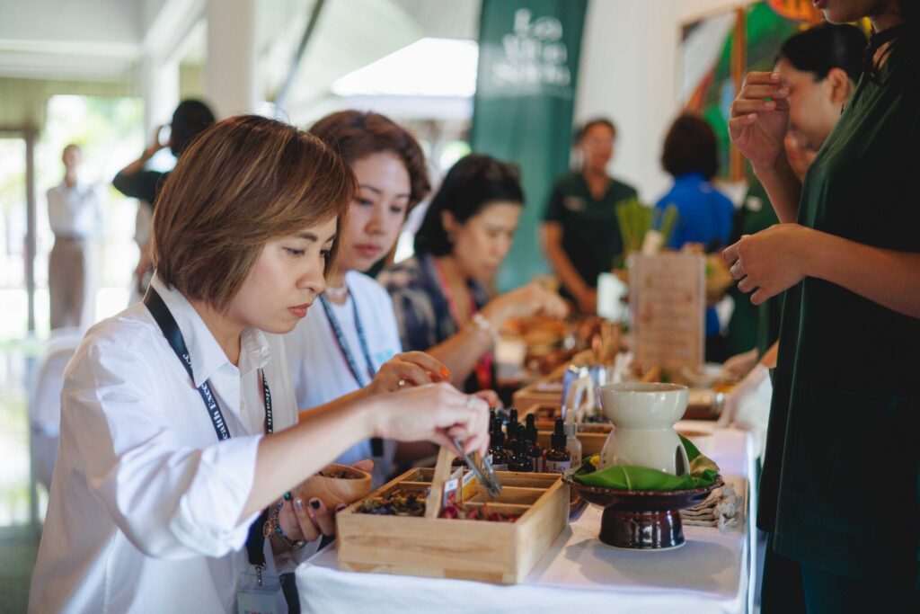 Participants explore Thai herbs and wellness products during a coastal wellness activity in Phang-nga.