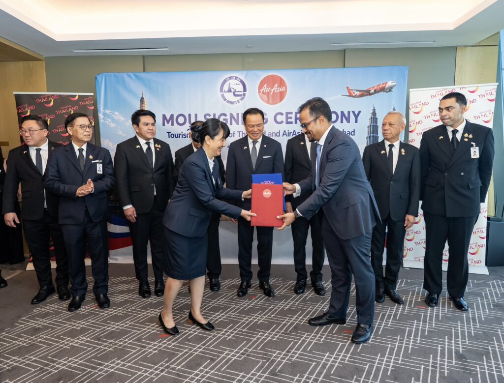 TAT and AirAsia Group representatives exchange MOU folders during the signing ceremony witnessed by senior Thai government officials.