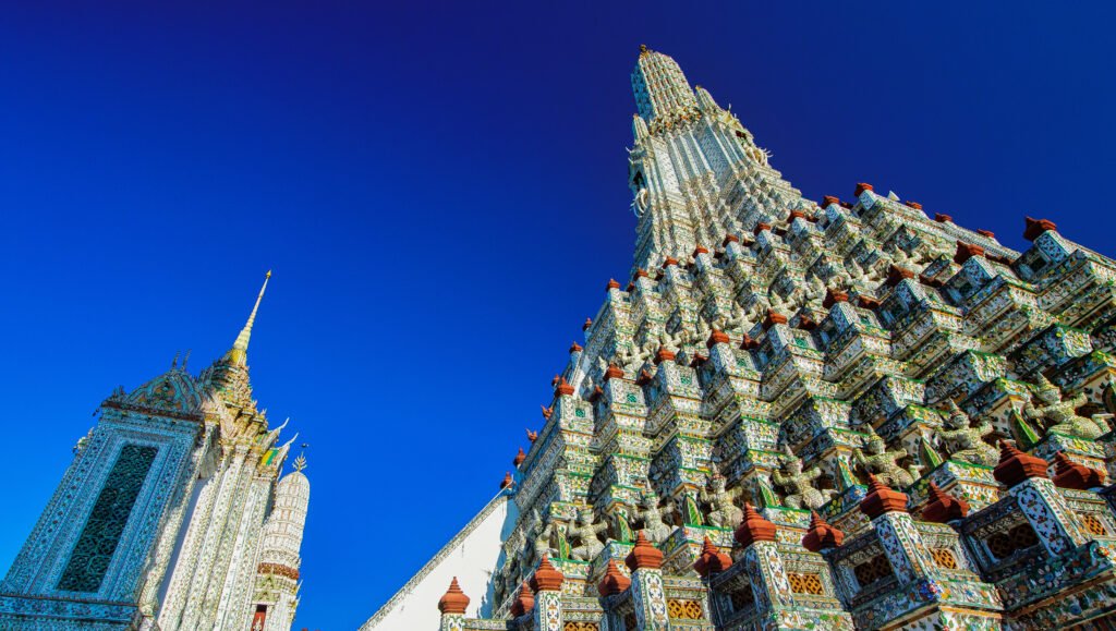 Ornate ceramic details of Wat Arun rise against a vivid blue sky in Bangkok.