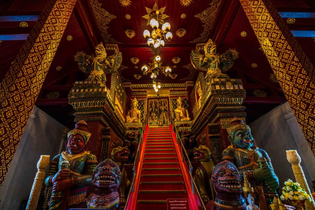 Ornate guardian statues and a ceremonial staircase inside Wat Phra Mahathat Woramahawihan.