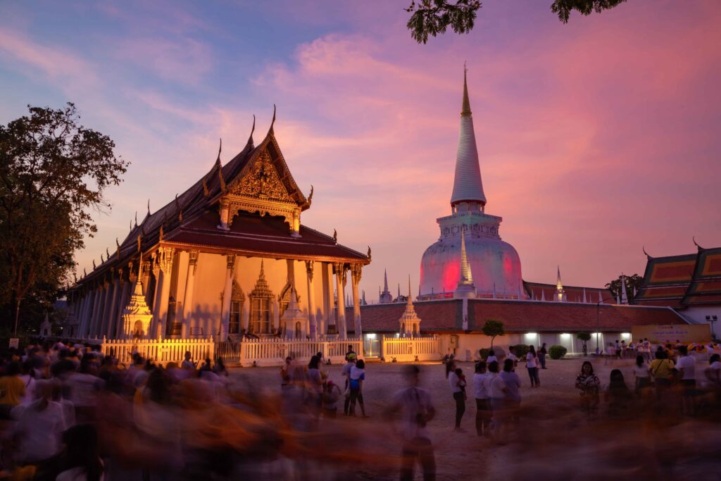 Wat Phra Mahathat Woramahawihan glows at sunset as visitors join a traditional Buddhist ceremony.