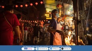 Street food vendor cooking over open flame in Yaowarat, Bangkok, under red Chinese lanterns, reflecting Chinese influence on Thai cuisine and vibrant night market culture.