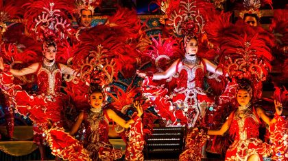 Molam performers in red costumes with feathered headdresses during vibrant show at Molam Festival 2025